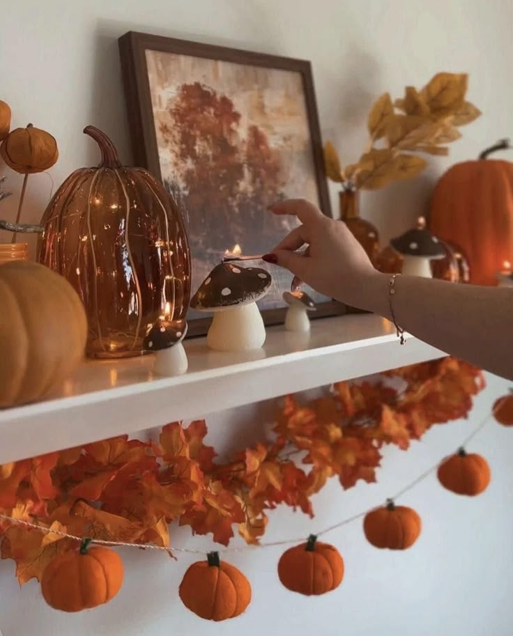 Autumn shelf decor with orange pumpkins, faux mushrooms, and fall leaves. Warm and cozy seasonal ambiance.