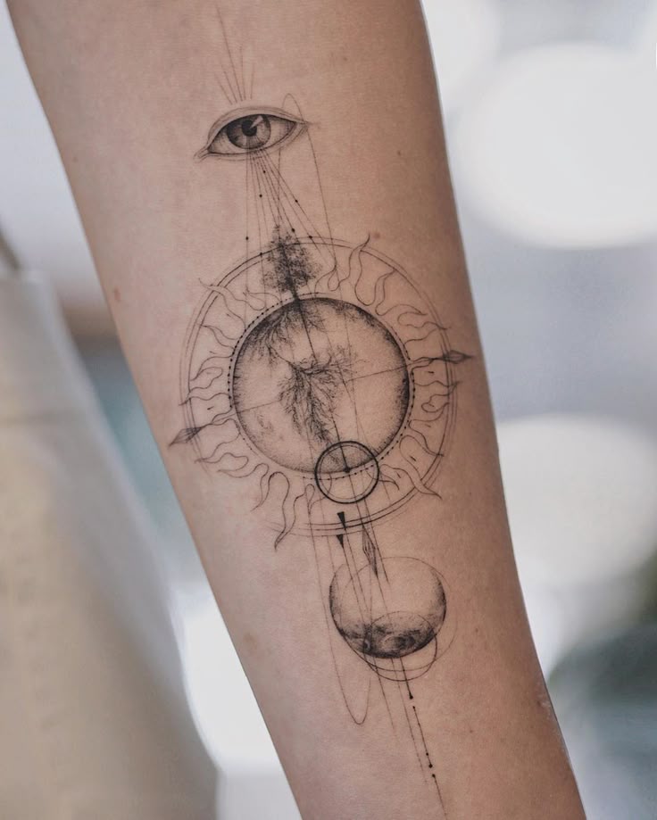 Geometric tattoo on forearm featuring eye, sun, moon, and abstract designs in black ink.