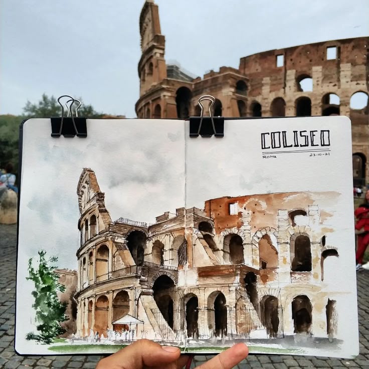 Sketch of the Colosseum in a notebook held up in front of the actual Roman Colosseum.
