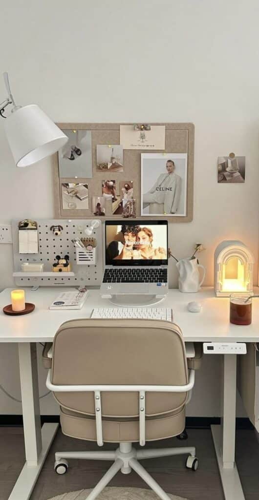 Modern home office setup with beige chair, laptop, mood board, and warm lighting. Cozy workspace inspiration.