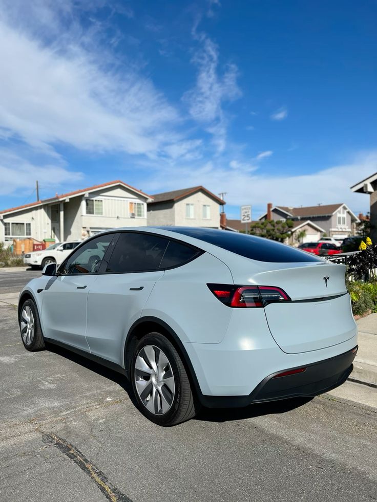 Electric car parked on suburban street under clear blue sky, showcasing sleek design and modern technology.