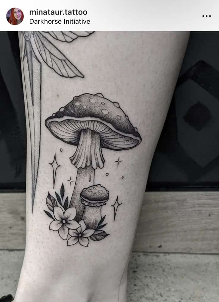 Tattoo of shaded mushrooms with flowers and stars on leg. Detailed linework design.