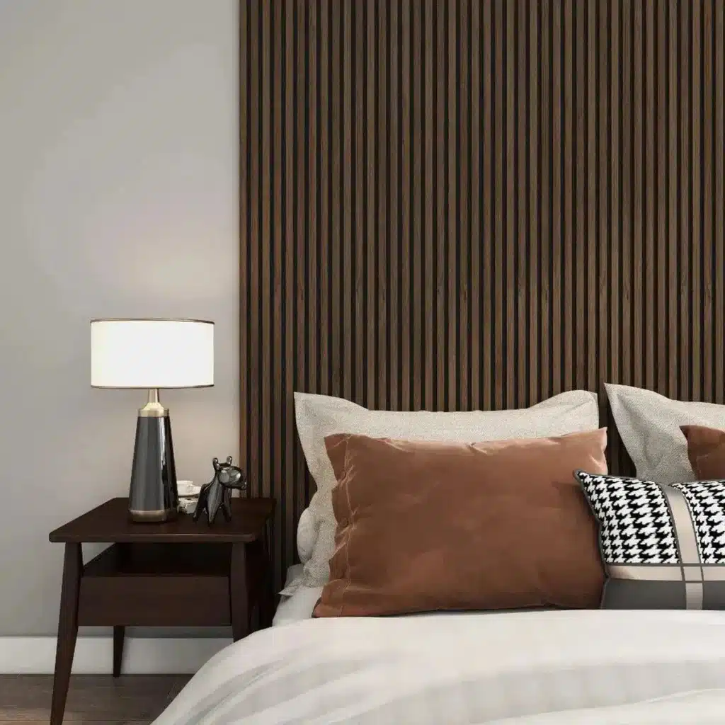 Modern bedroom with a dark wood headboard, plush pillows, nightstand, stylish lamp, and houndstooth accent pillow.