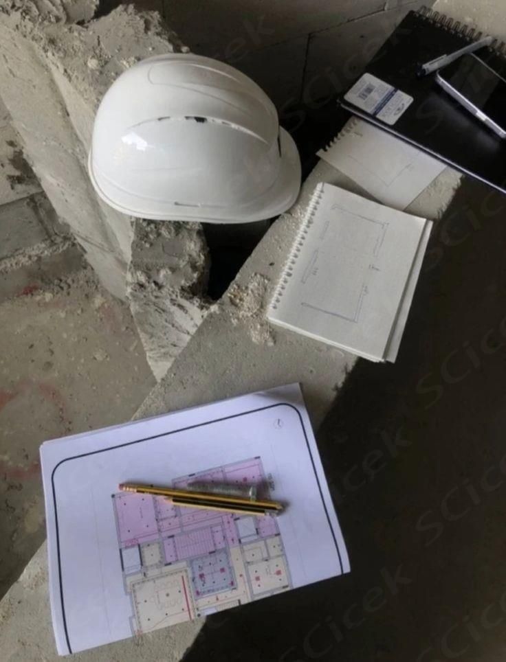 Construction site scene with hard hat, architectural plans, and sketches on concrete surface, planning tools visible.