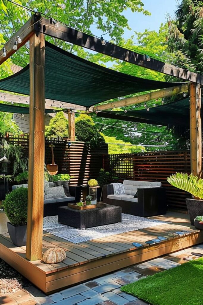 Outdoor patio with cozy seating, shaded pergola, lush greenery, and string lights creating a relaxing backyard oasis.