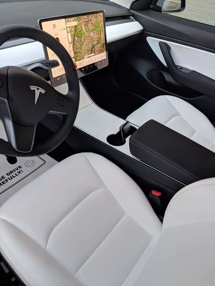 Black Model 3 with white interior Modern Tesla car interior with white seats and large central touchscreen displaying a map. | Sky Rye Design Modern Tesla car interior with white seats and large central touchscreen displaying a map.