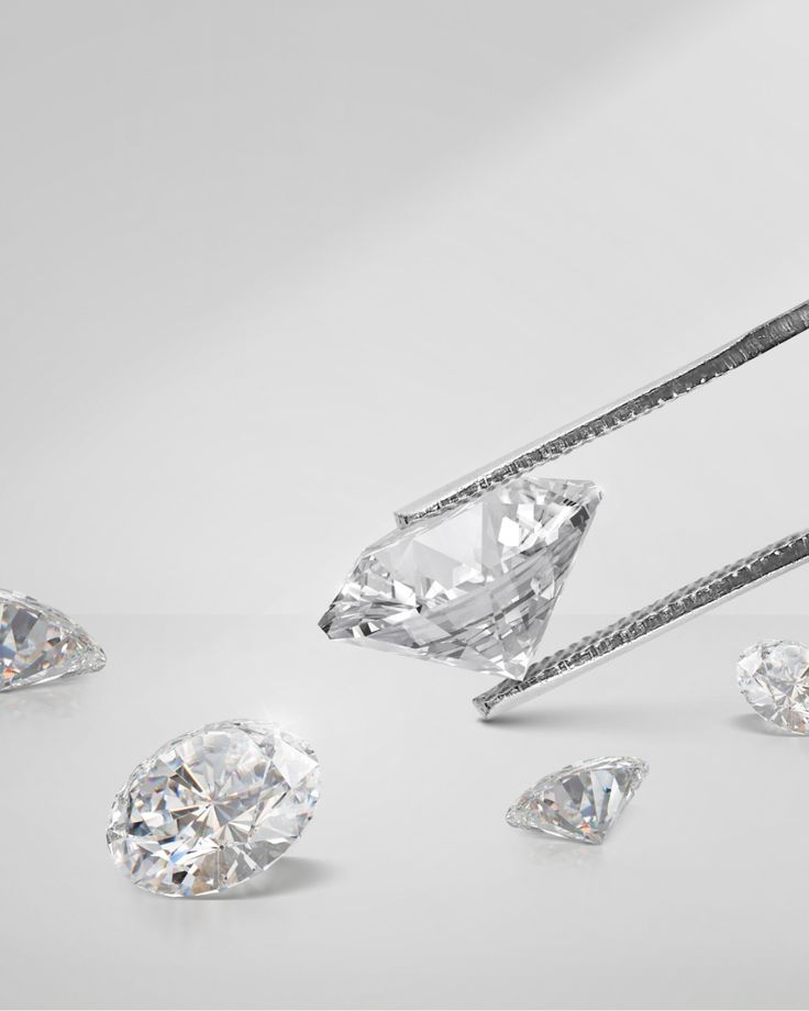 Tweezers holding a sparkling diamond among loose gems on a white background.