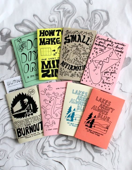 Colorful zines arranged on a table, featuring illustrations and titles like DIY and Affirmations.