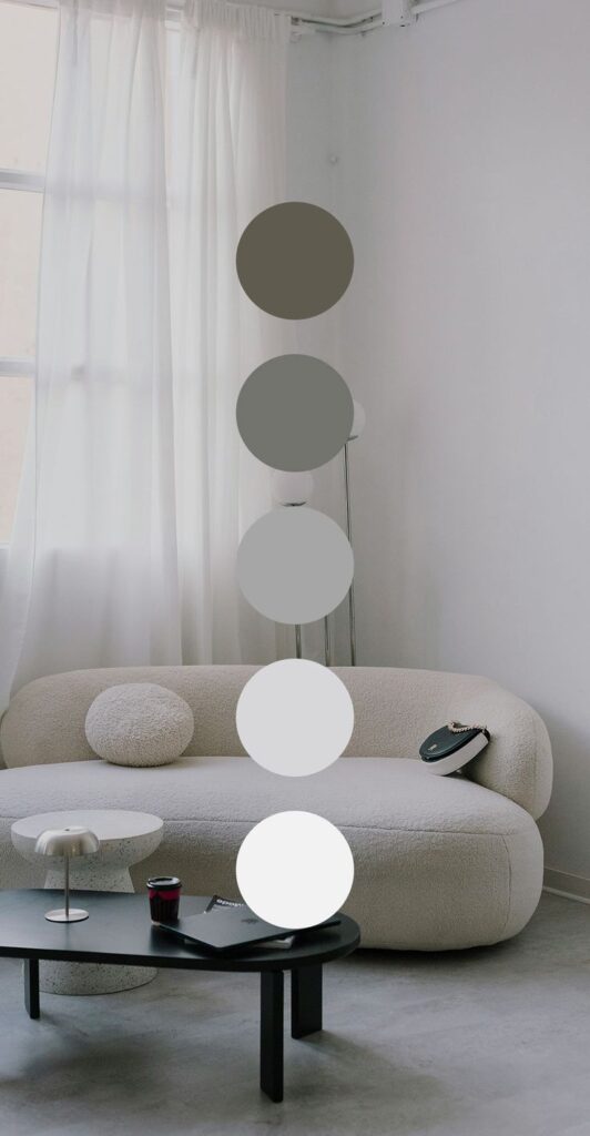 Modern living room with neutral decor, featuring a cozy sofa and elegant coffee table with laptop and cup.
