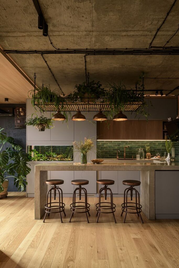 Modern kitchen with island, wooden stools, hanging plants, and industrial lighting for a stylish, eco-friendly design.