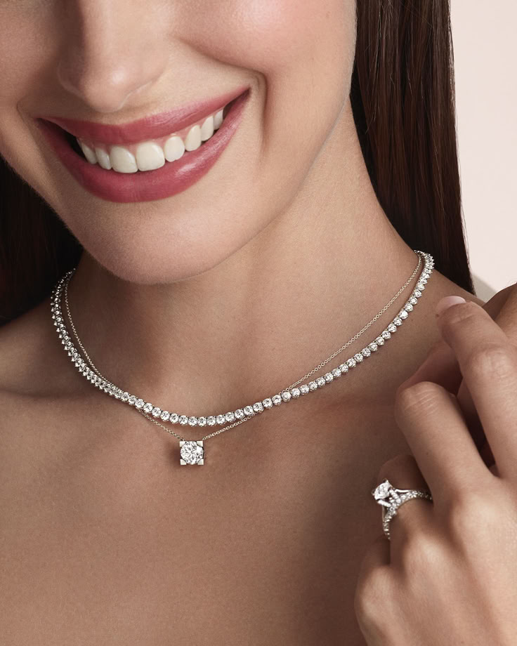Smiling woman wearing a diamond necklace and ring, showcasing elegant jewelry for special occasions.
