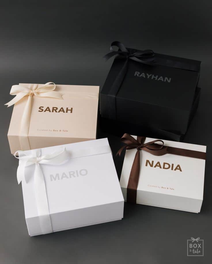 Four personalized gift boxes with ribbons, labeled Sarah, Rayhan, Mario, and Nadia, on a dark background.