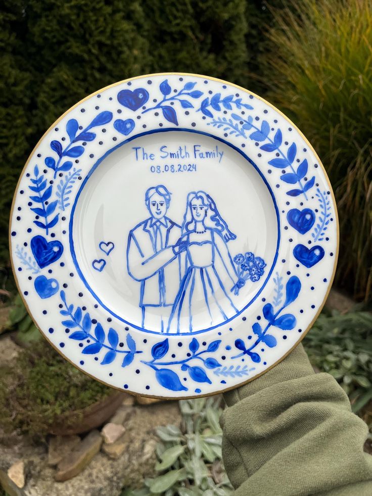 Custom hand-painted wedding plate with blue floral design and couple illustration, personalized with family name and date.