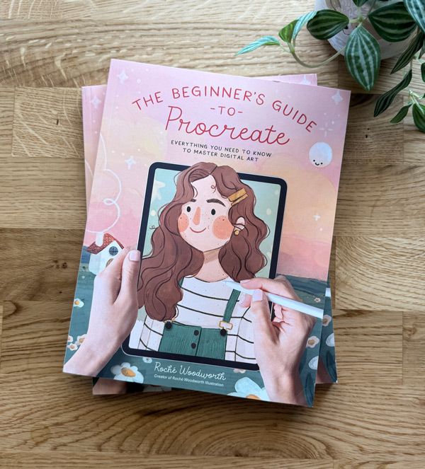 The Beginner's Guide to Procreate book on mastering digital art with illustrated cover on a wooden table.