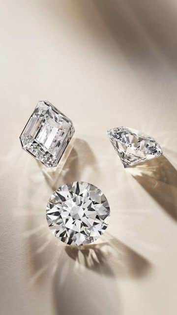 Three sparkling gemstones: round, emerald, and marquise cuts on a light background, showcasing clarity and brilliance.