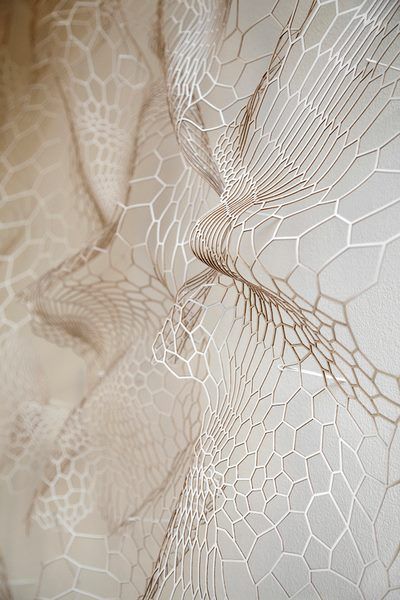 Abstract wavy pattern with hexagonal mesh design in neutral tones, creating a textured and layered visual effect.
