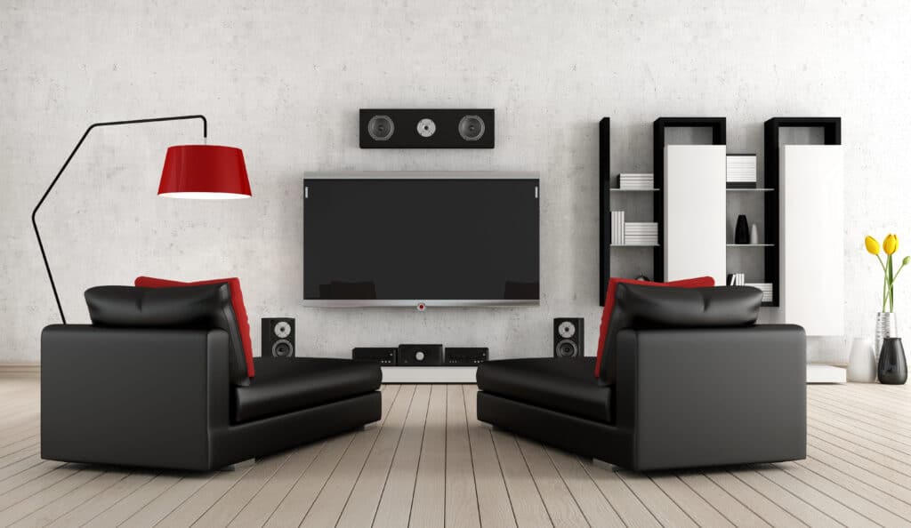 Modern living room with black and red sofas, flat-screen TV, sound system, shelves, and a stylish floor lamp.