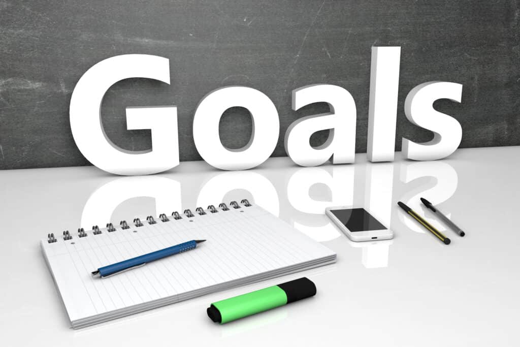 Notebook and pen on desk with 'Goals' text background, symbolizing planning and productivity.