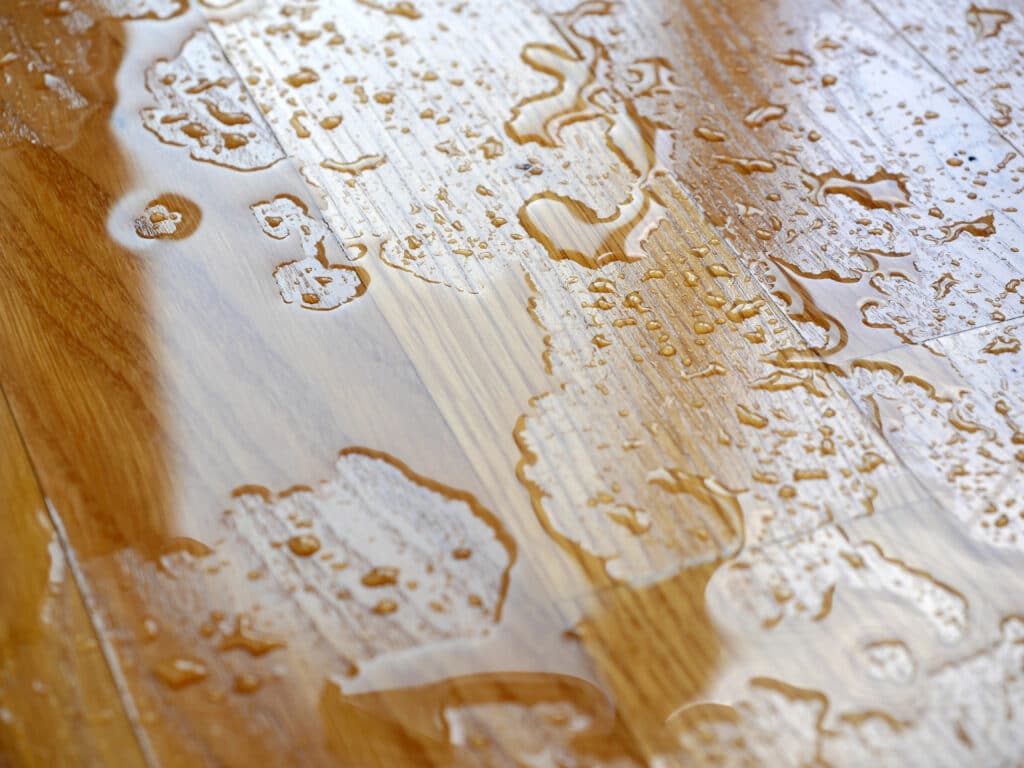 Water droplets on wooden surface, showcasing water resistance and protection of hardwood floors.