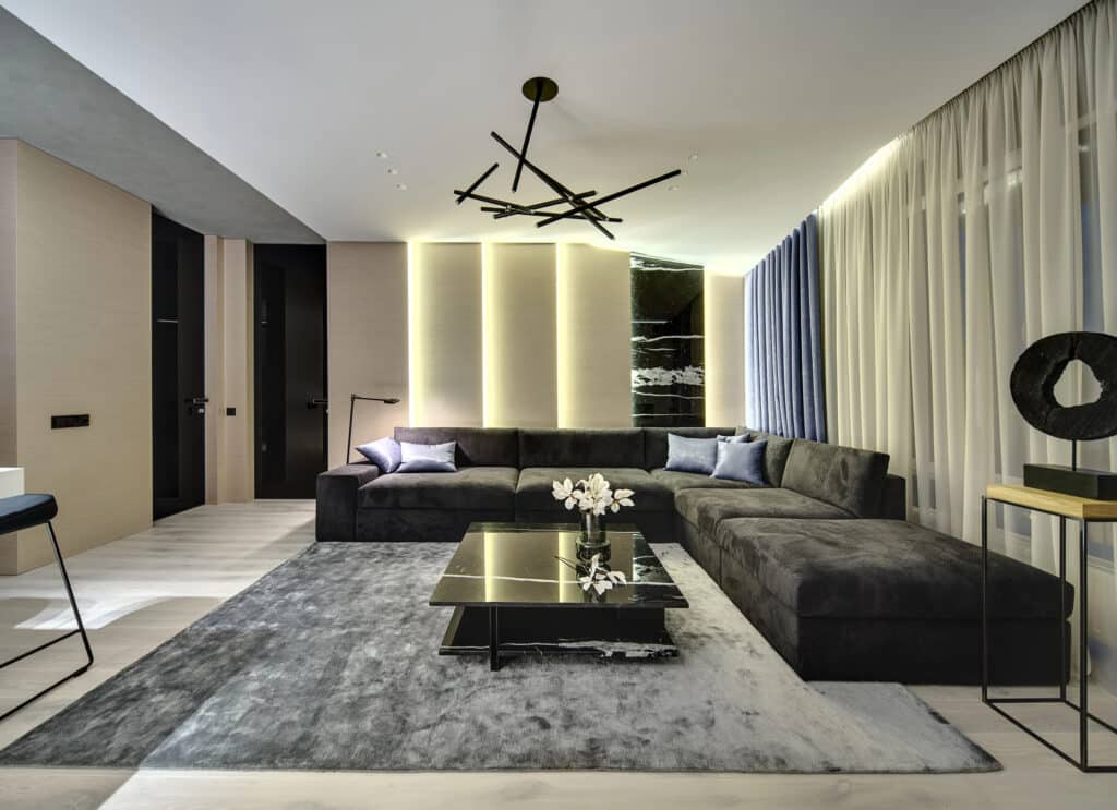Modern living room with gray sectional sofa, chic lighting, and elegant decor.