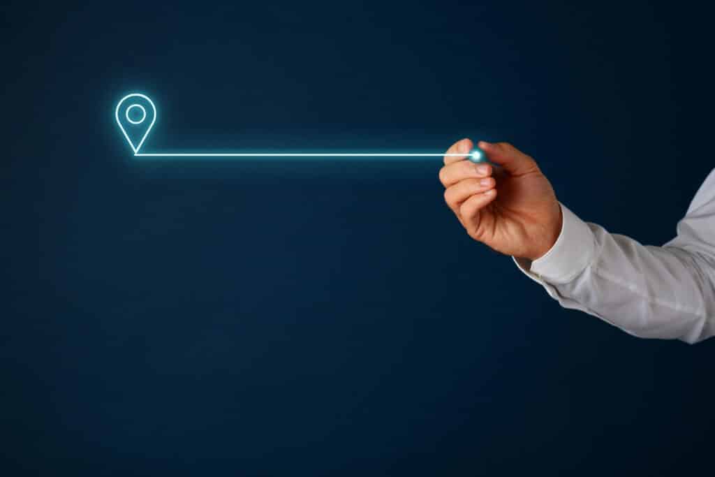 Hand drawing glowing location pin on dark background, symbolizing navigation and digital mapping.
