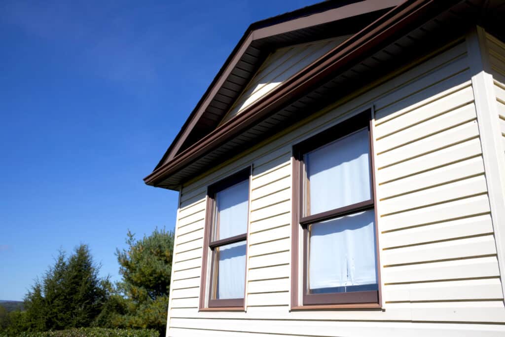House exterior with siding and two windows against a clear blue sky.