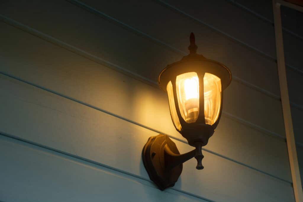 Vintage outdoor wall lantern illuminating a blue siding exterior.