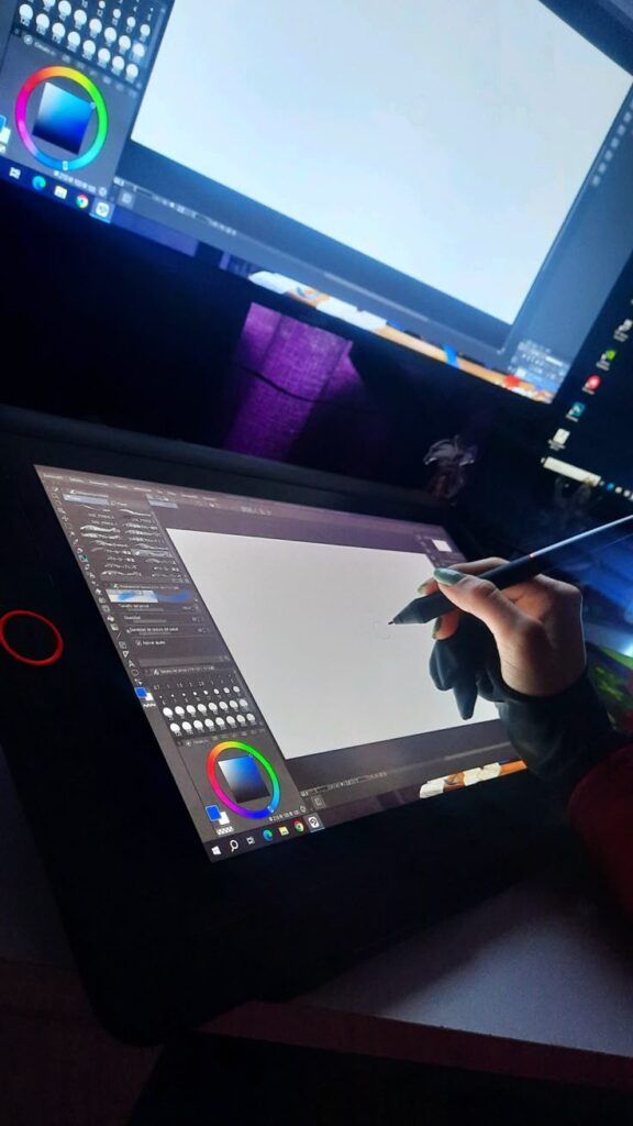Artist using graphics tablet for digital drawing in software with color palette on screen.