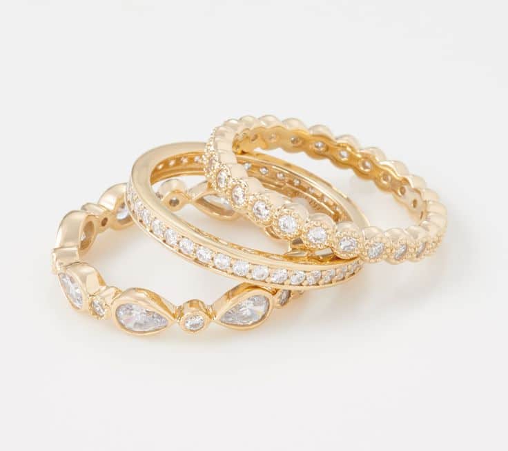 Three elegant gold rings with diamonds on a white background, showcasing intricate design and sparkle.
