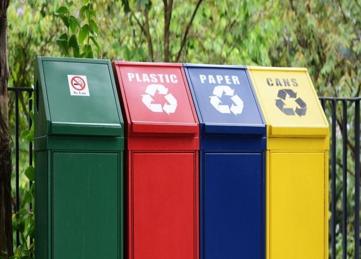 Different Waste Management Techniques to Trim Down Pollution LatestNews TrendingNow WasteManagment Pollution Colorful recycling bins for plastic, paper, and cans in a row outdoors against green foliage background. | Sky Rye Design Colorful recycling bins for plastic, paper, and cans in a row outdoors against green foliage background.