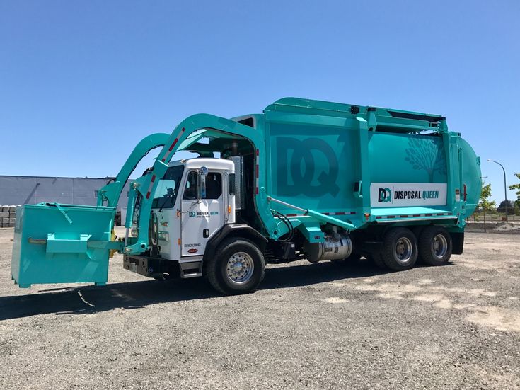 Turquoise garbage truck parked on a sunny day in an open lot, featuring the Disposal Queen logo.