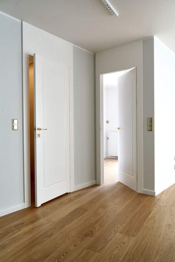 Modern interior with open white doors and wooden flooring for a minimalist look.