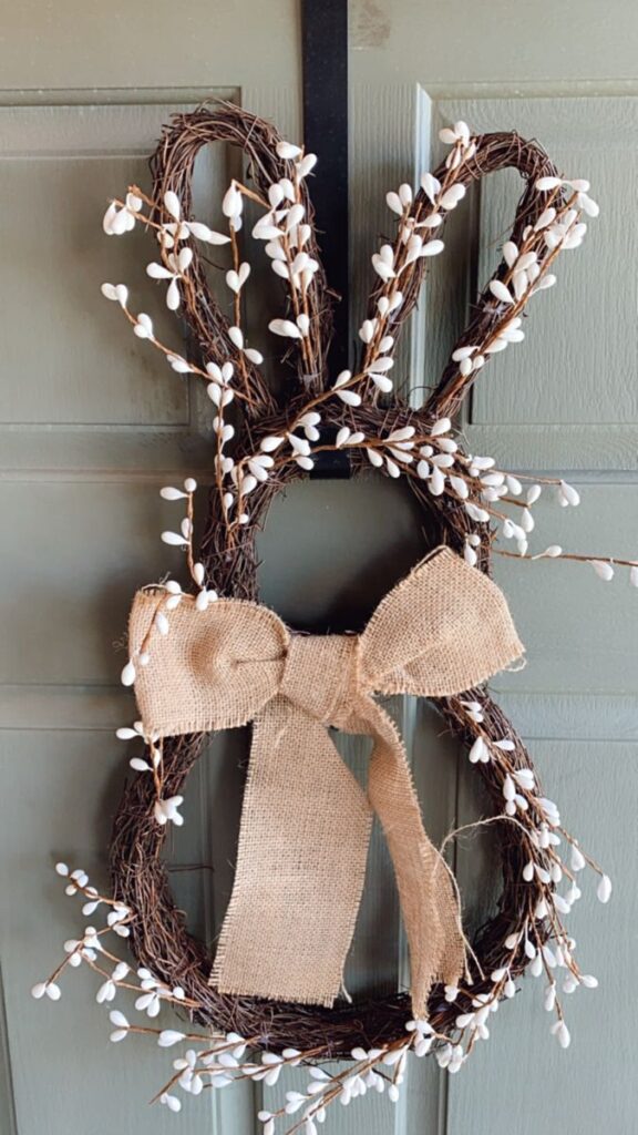 Easter bunny wreath with burlap bow and white florals on a wooden door. Perfect spring decor idea.