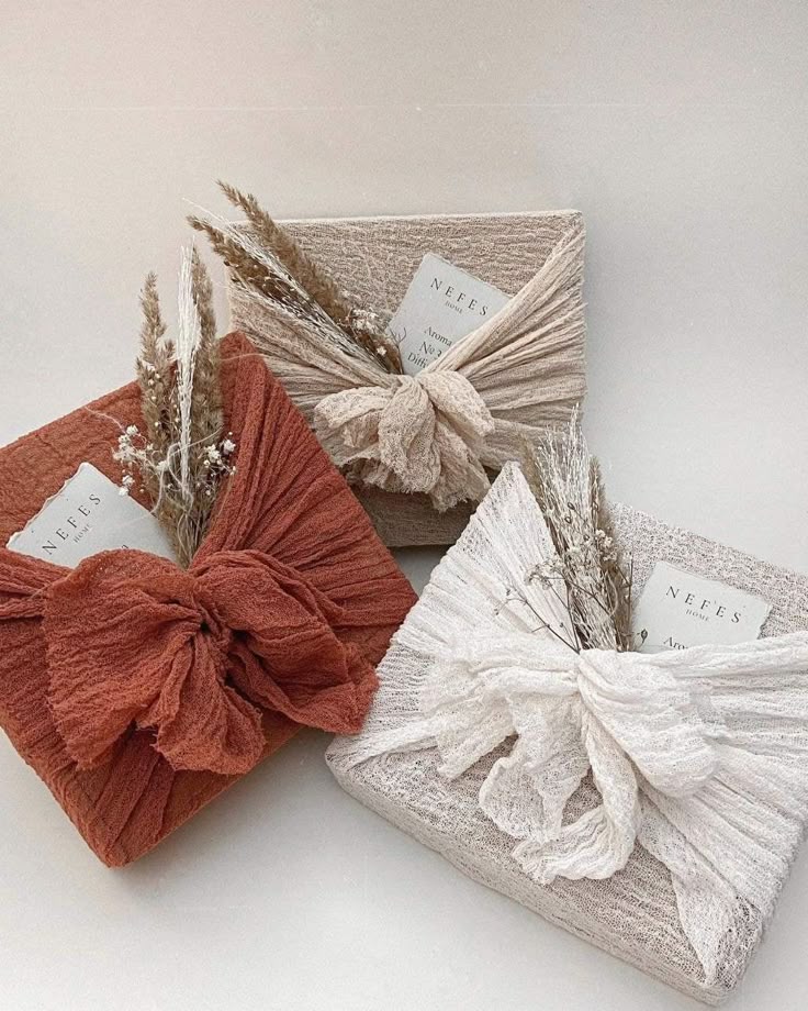 Eco-friendly gift boxes wrapped in textured fabric with decorative dried flowers for a sustainable presentation.