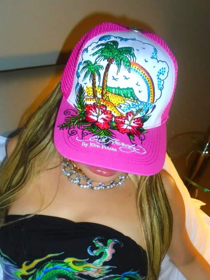Woman wearing a colorful Ed Hardy cap with tropical island design and vibrant accessories.