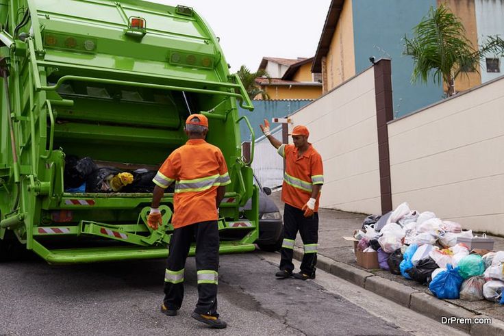 Keeping the city clean a team of garbage collectors Two sanitation workers in orange uniforms collecting residential garbage into a green truck on a neighborhood street. | Sky Rye Design Two sanitation workers in orange uniforms collecting residential garbage into a green truck on a neighborhood street.