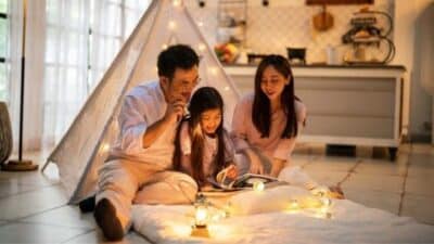 Family reading together inside a cozy tent with warm string lights in a modern kitchen setting.