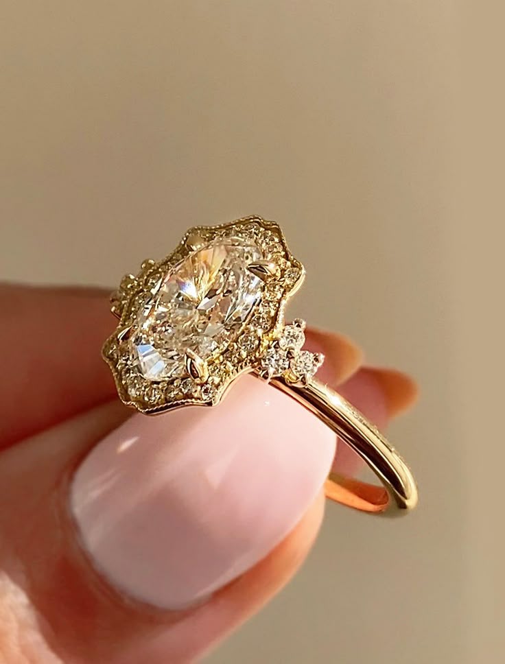 Elegant oval diamond ring with intricate gold setting held by fingers under soft lighting.