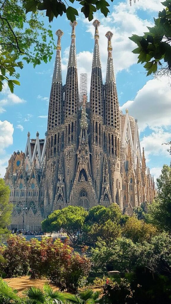 Majestic view of La Sagrada Familia in Barcelona under a clear blue sky, surrounded by lush greenery.