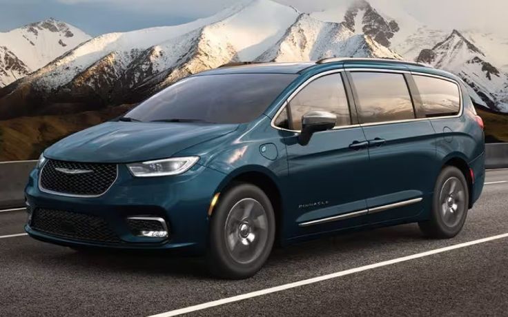 Blue minivan on a mountain road with snow-capped peaks in the background, showcasing adventure and style.