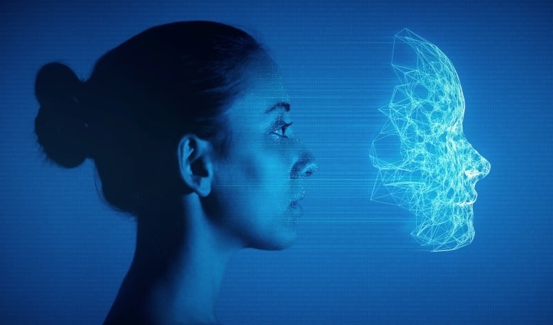 Woman facing 3D digital facial mesh, representing AI technology and digital transformation.