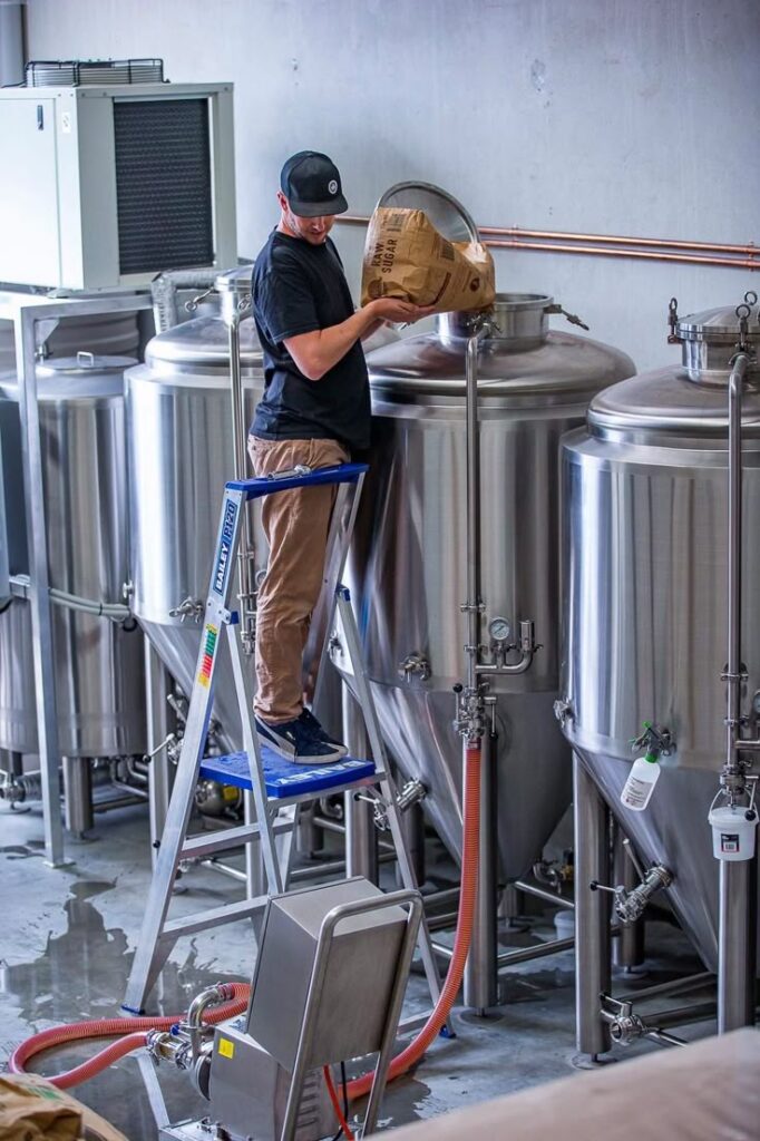 Feedback from Australian customers Brewer adding ingredients to beer fermentation tank in brewery facility. | Sky Rye Design Brewer adding ingredients to beer fermentation tank in brewery facility.