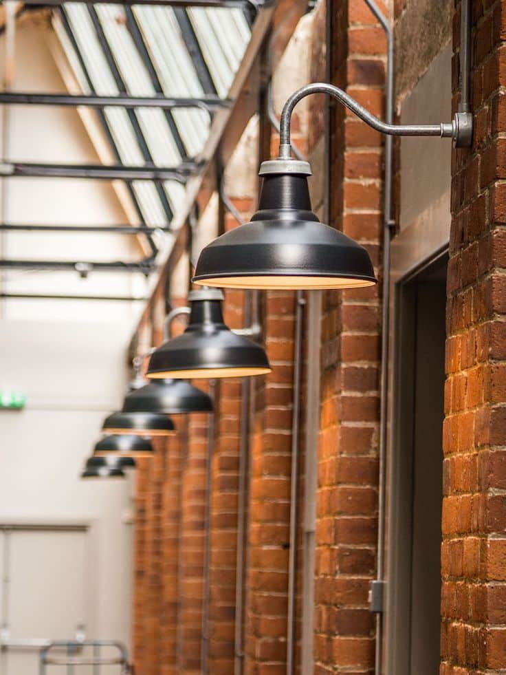 Industrial-style black lamps on a brick wall in a corridor, showcasing modern architectural design.