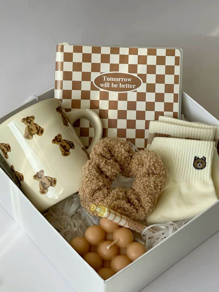 Gift box with mug, notebook, socks, scrunchie, and candle. Checkered notebook says Tomorrow will be better.