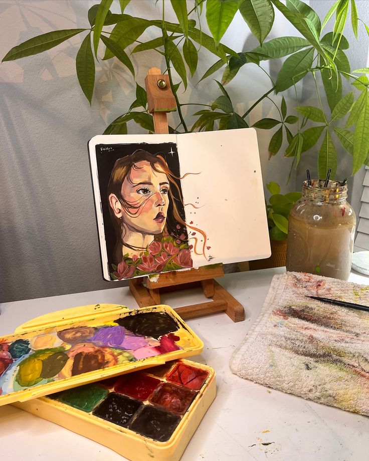 Painting of a woman on canvas in an art studio, surrounded by plants and watercolor paints.