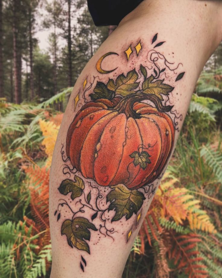Pumpkin tattoo with leaves and stars on leg, set in a forest background. Perfect blend of nature and art.