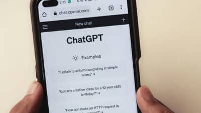 Person holding a smartphone displaying the ChatGPT website with example prompts onscreen.