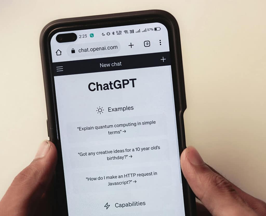 Person using ChatGPT app on smartphone for examples and capabilities.