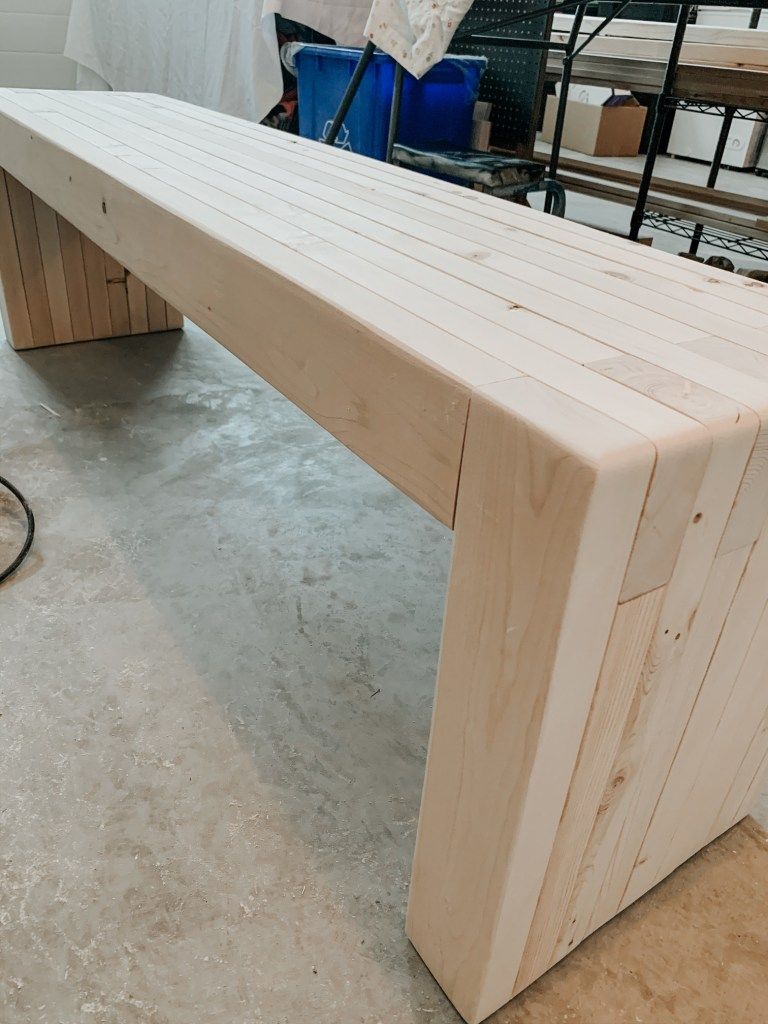 Modern wooden bench in a workshop, showcasing clean lines and light wood finish.