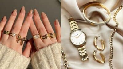 Hands wearing gold rings; beside, a gold watch, bracelet, and earrings on a soft fabric background.